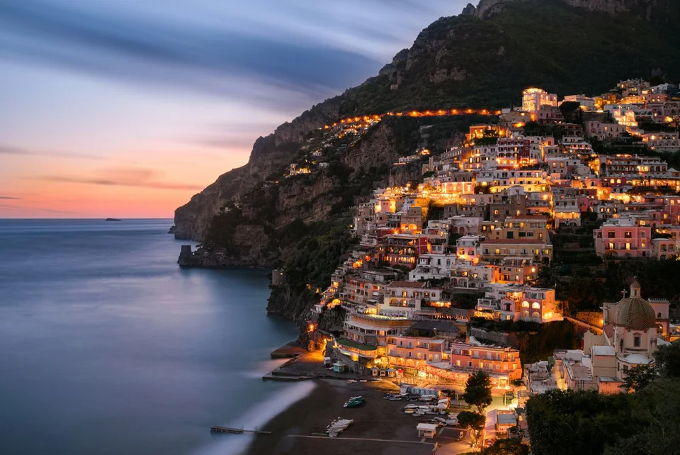 Positano’s illuminated hillside and beach beside the sea at dusk