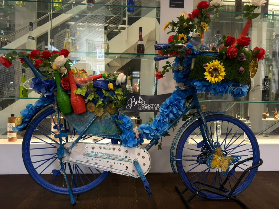Uma bicicleta azul decorada com flores diante de uma loja