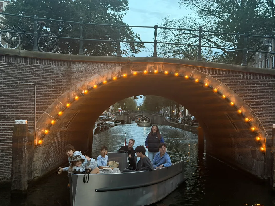 Um barco passando sob uma ponte iluminada de um canal