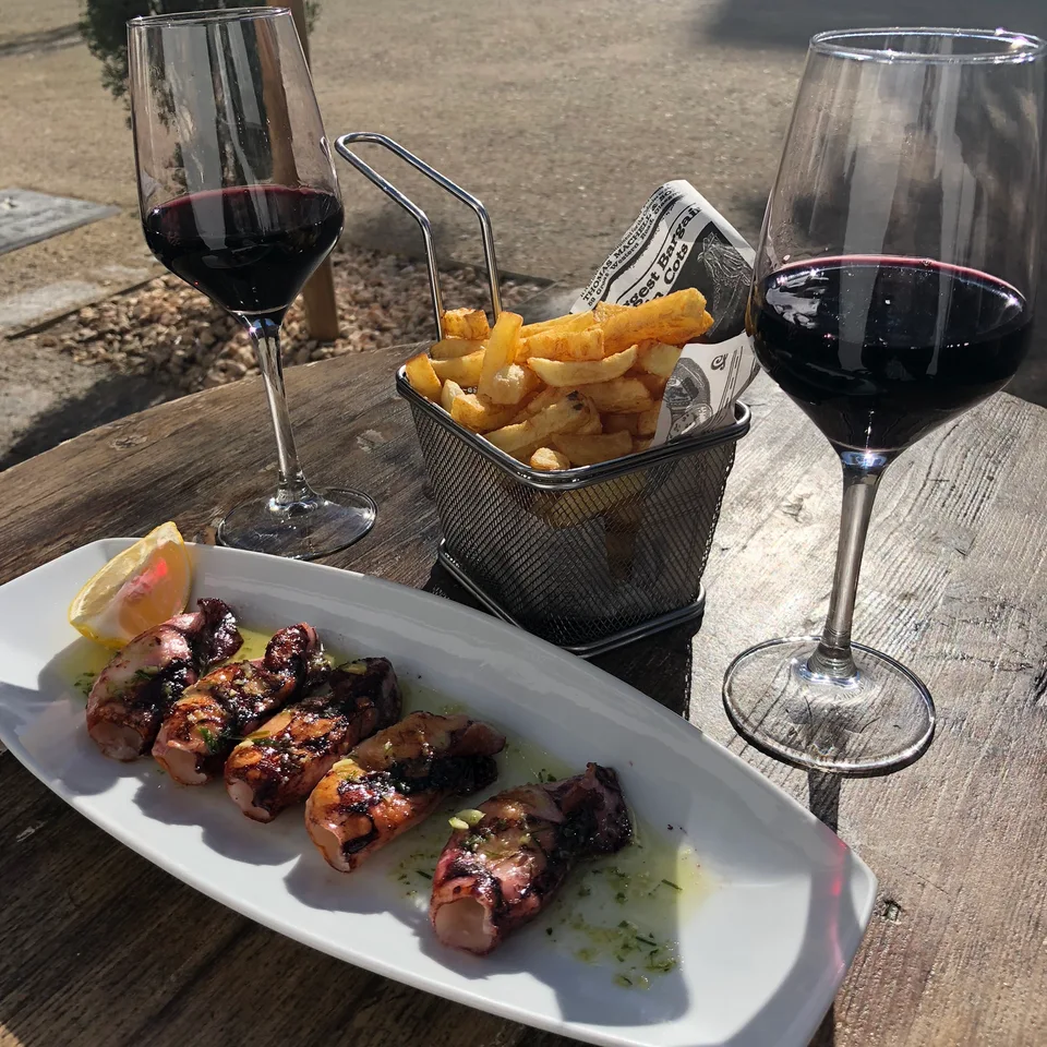 Skewers, fries and red wine on an outdoor dinner table