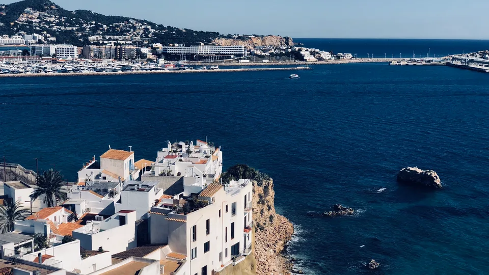 White Ibiza rooftops descending toward the blue harbor