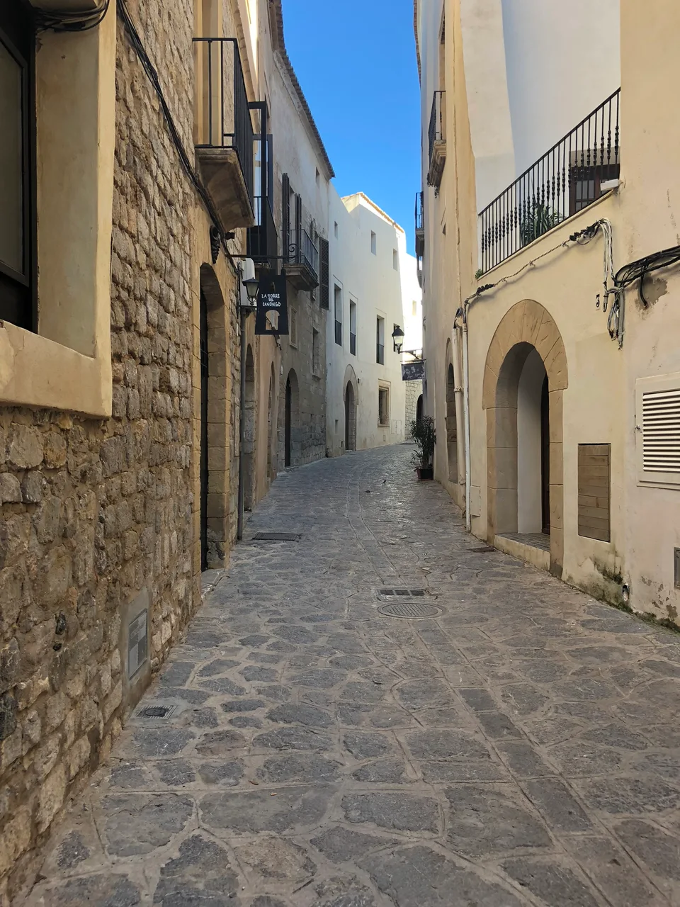 A narrow paved lane between white walls in Dalt Vila