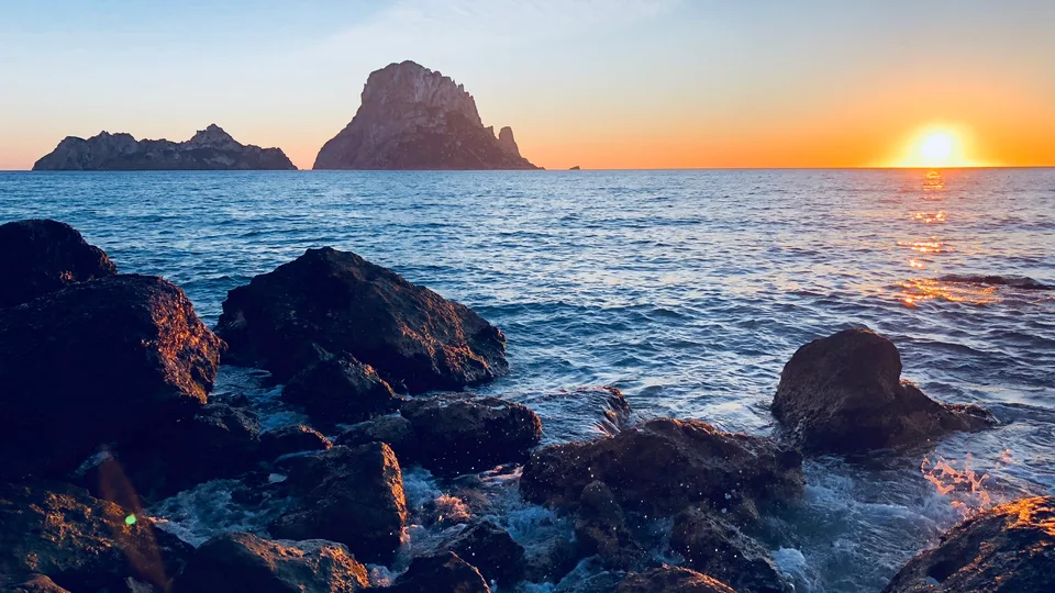 The sun setting beside a rocky islet off Ibiza