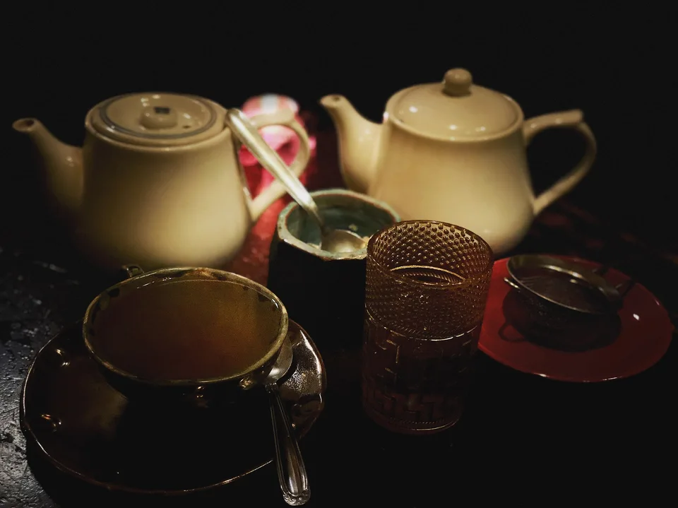 Teapots and cups arranged on a dark table