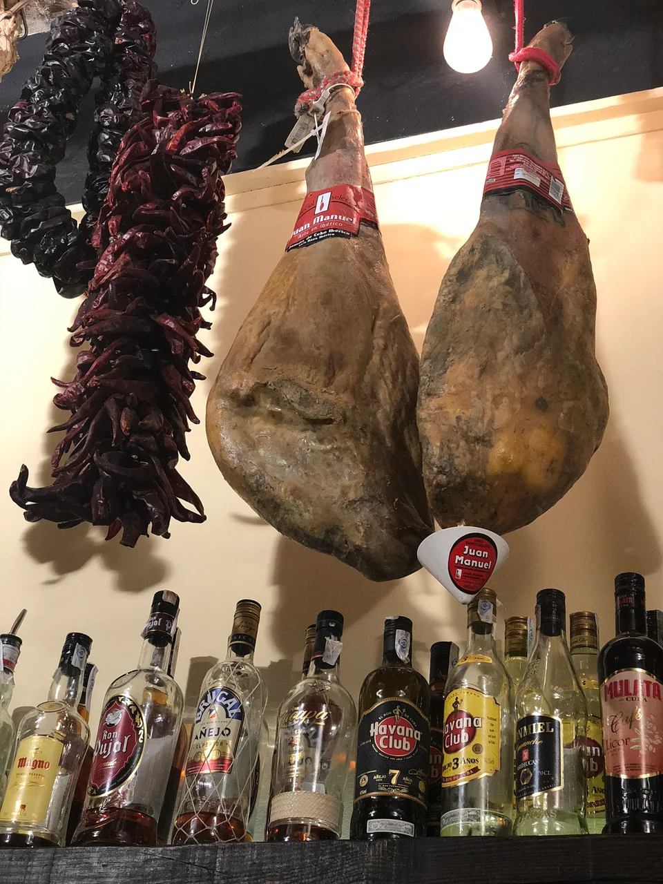 Hanging cured ham and bottles inside a Barcelona bar