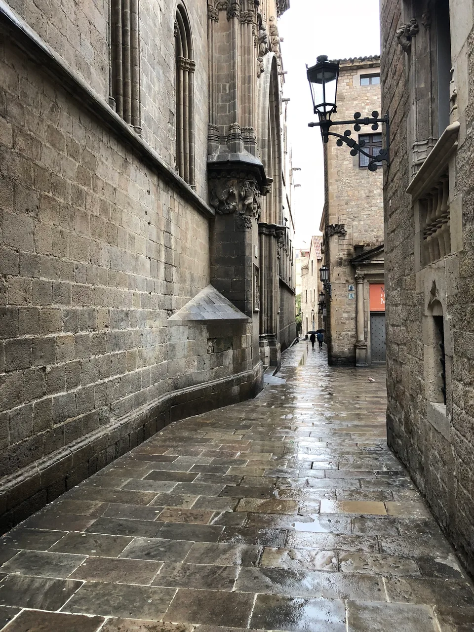 A wet narrow lane between old stone buildings in Barcelona