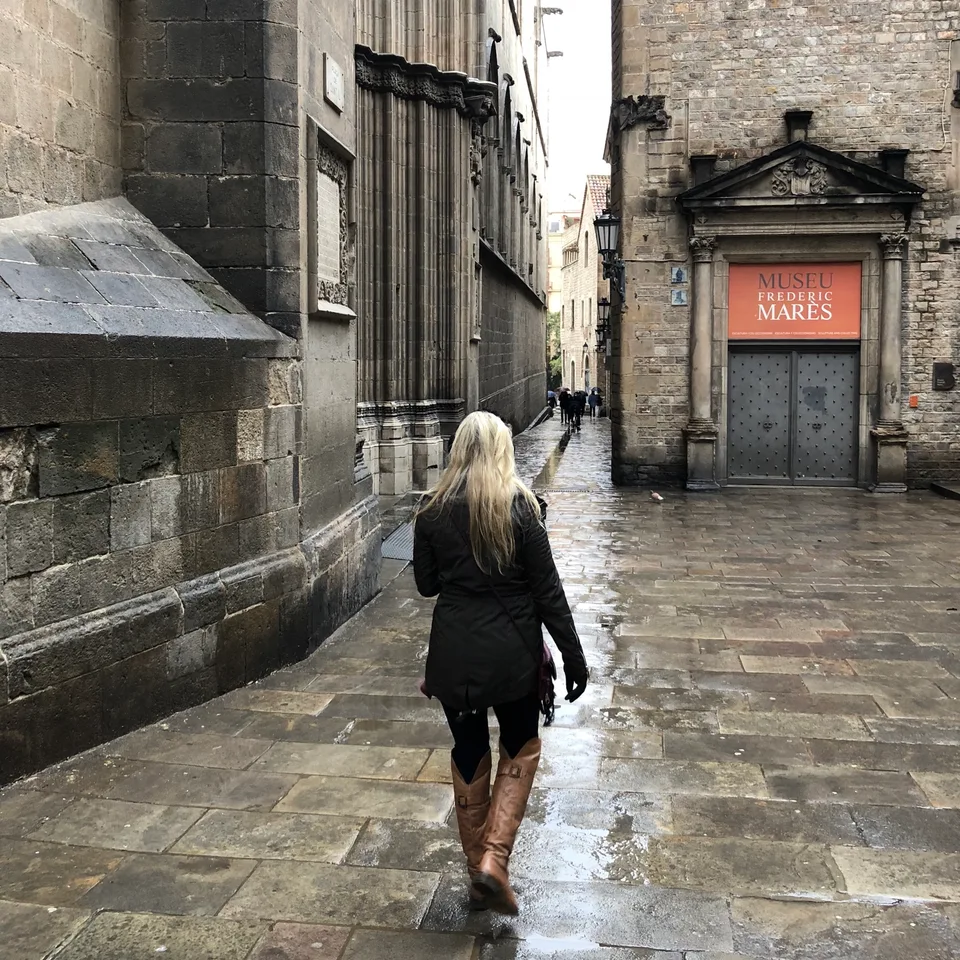 Kristin walking away along a rain-darkened old-city lane