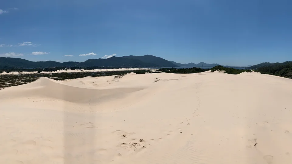 Pale dunes with dark green hills on the horizon near Joaquina