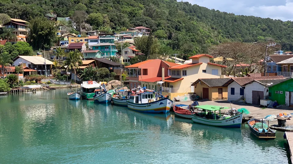 Colorful fishing boats moored beside houses along Barra da Lagoa’s channel