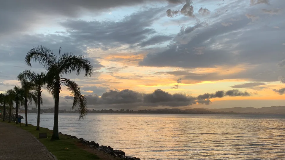 Palms and sheltered water under a yellow-and-gray sunset sky