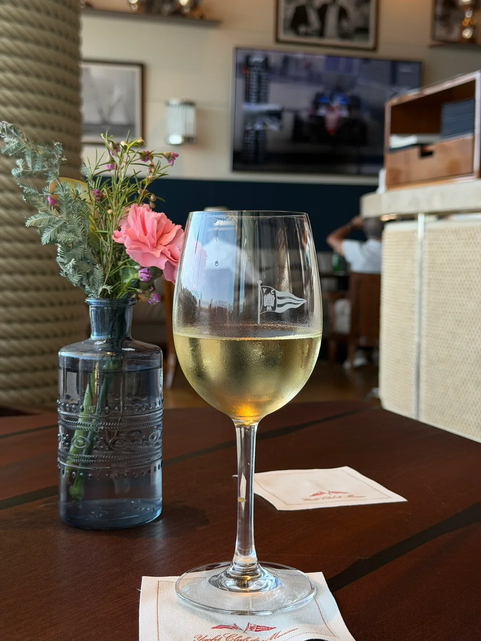 A glass of white wine beside flowers and a restaurant menu