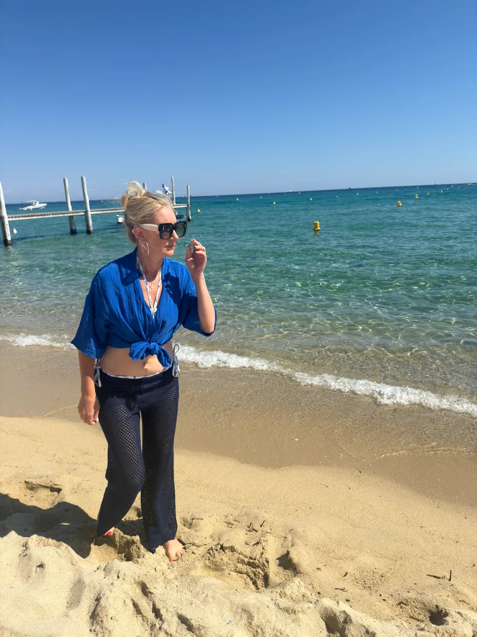 Kristin standing on the sand beside clear Mediterranean water
