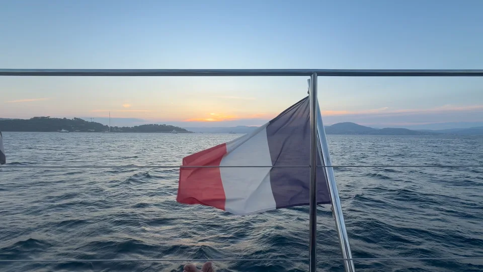 A French flag above the sea at sunset from a boat