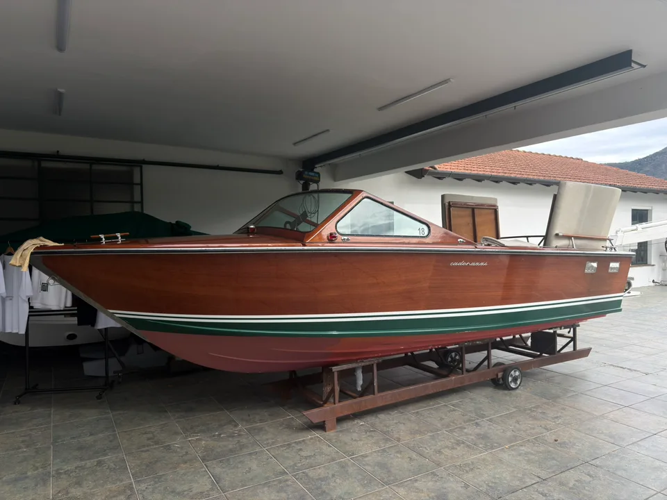 Um barco de madeira polida guardado sob o telhado de uma garagem náutica