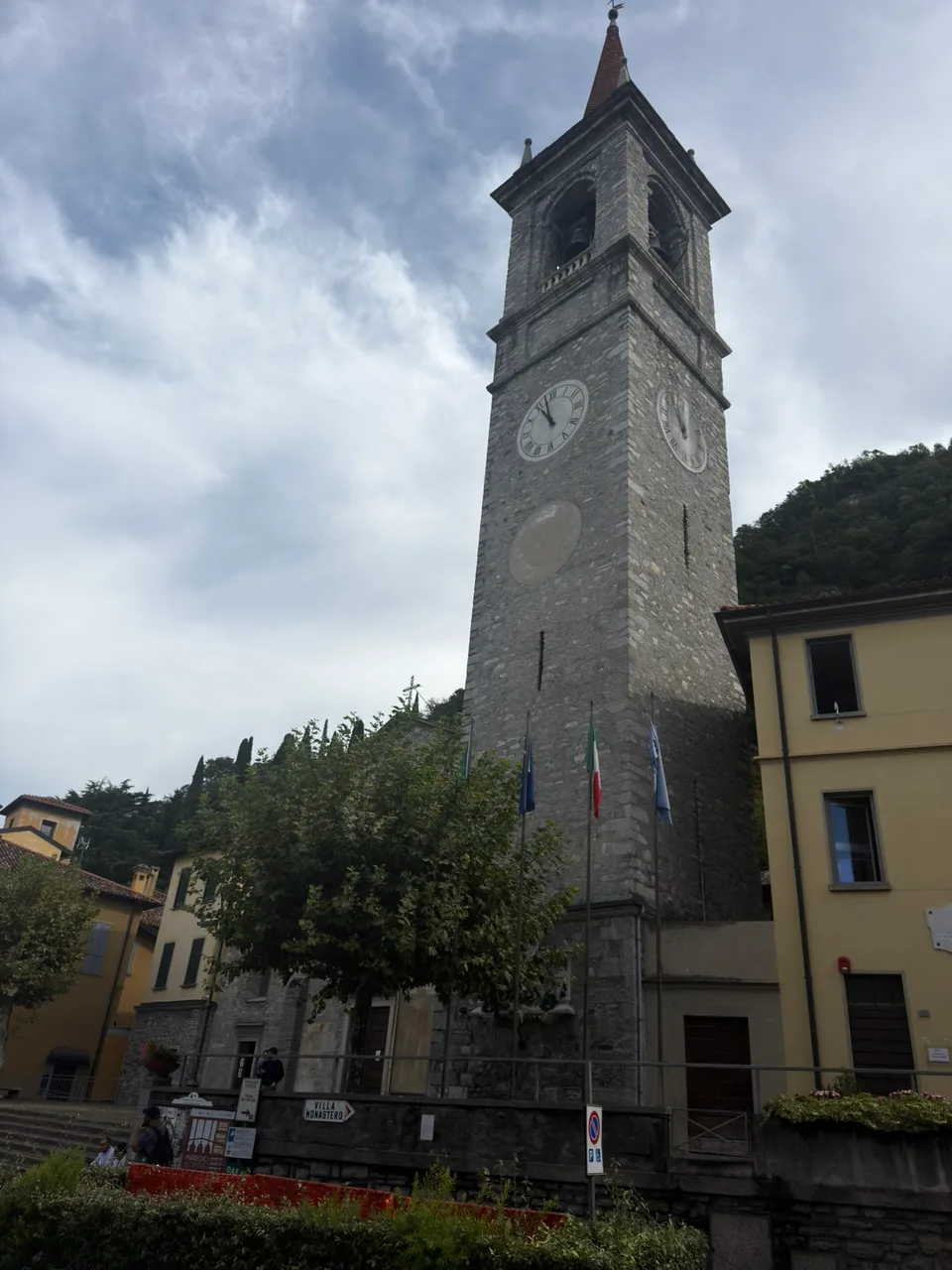 Uma torre de igreja em pedra junto a uma praça