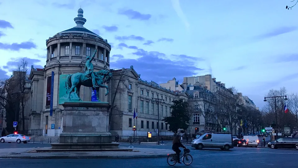 Uma fonte e prédios de pedra ornamentados na Place de la Concorde sob o céu azul da noite