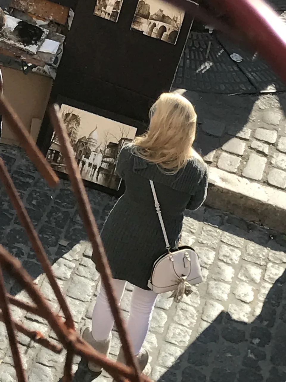 Kristin examinando pinturas em Montmartre, fotografada de cima