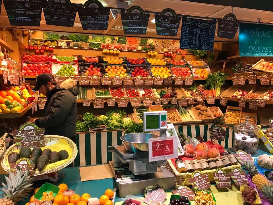 Uma banca de bairro cheia de frutas, verduras e placas escritas à mão