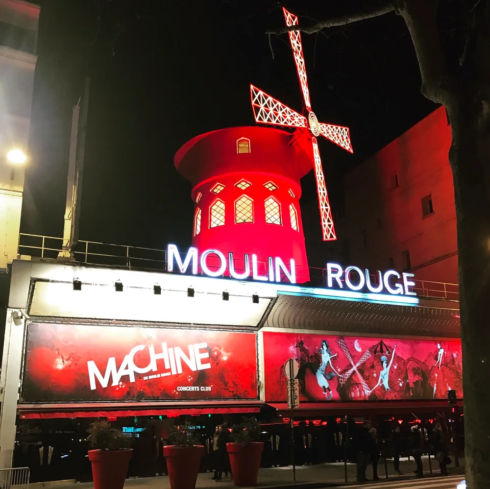 O moinho vermelho e a fachada iluminada do Moulin Rouge à noite