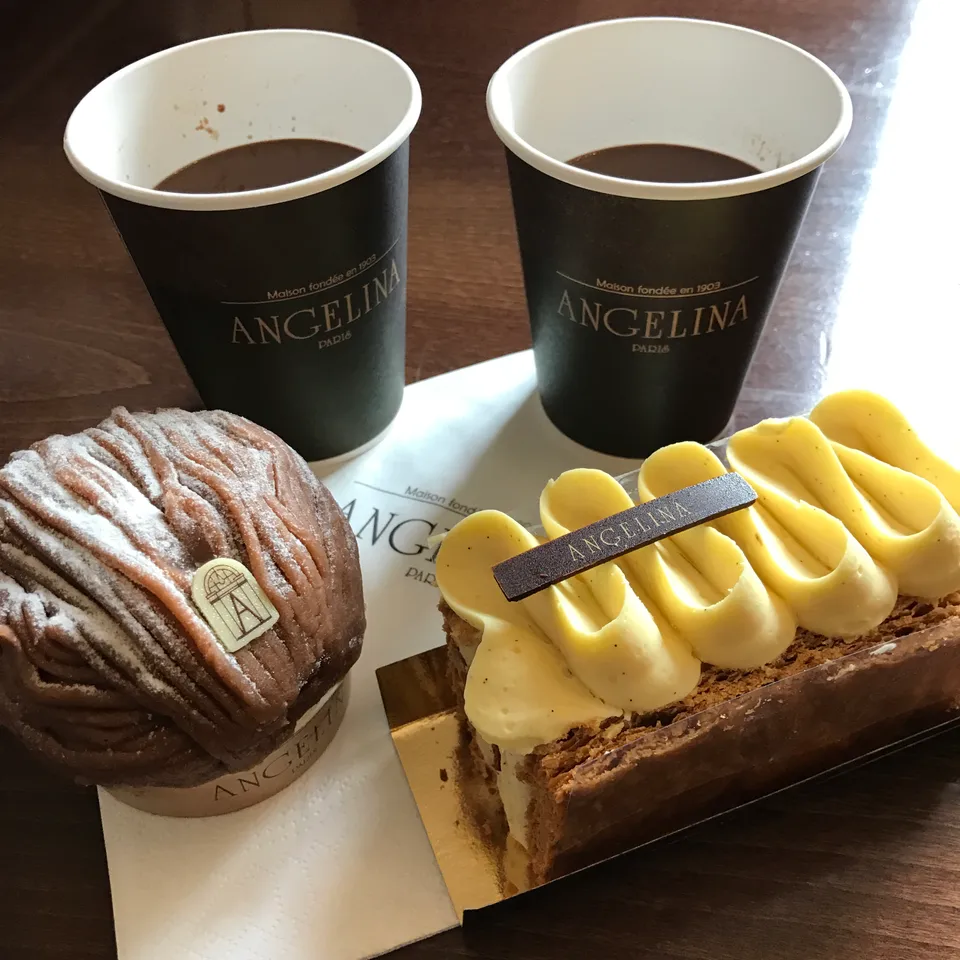 Two cups of hot chocolate and carefully decorated pastries in a takeaway box