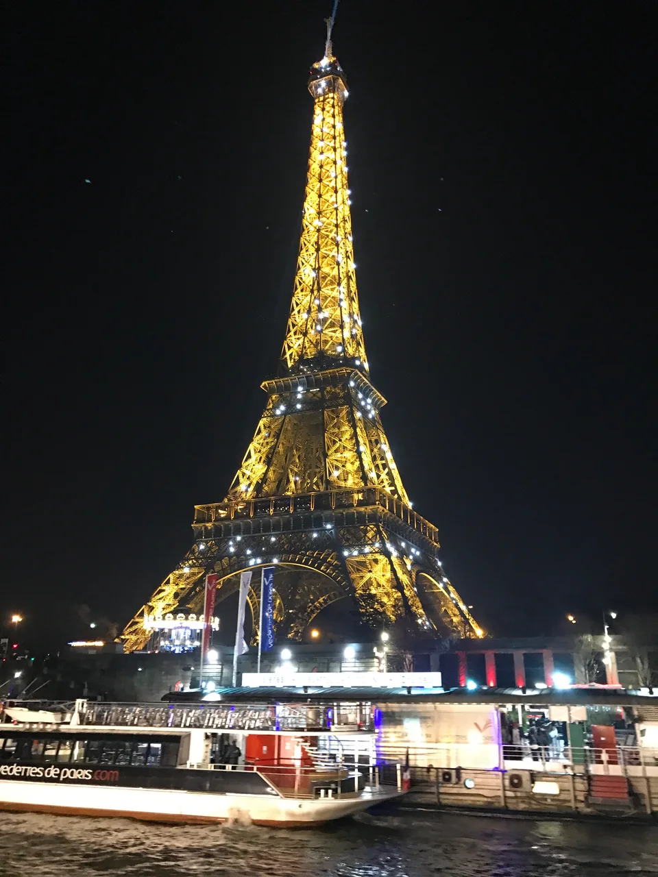 A Torre Eiffel inteira iluminada contra o céu preto da noite