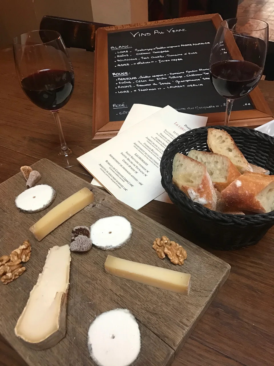Uma tábua de queijos, pão e uma taça de vinho tinto numa mesa de restaurante