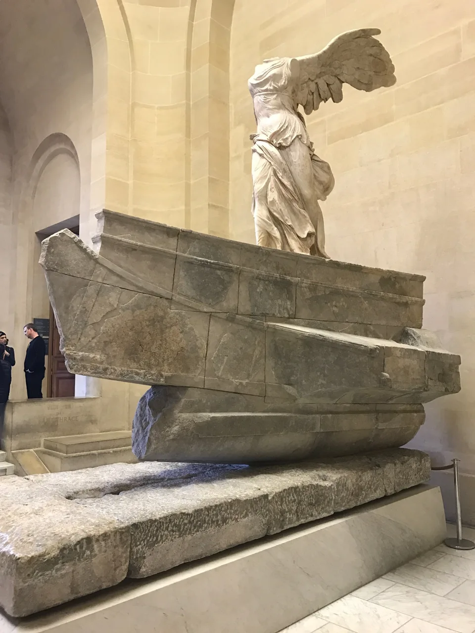 A Vitória de Samotrácia sobre sua base em forma de navio acima da escadaria do Louvre