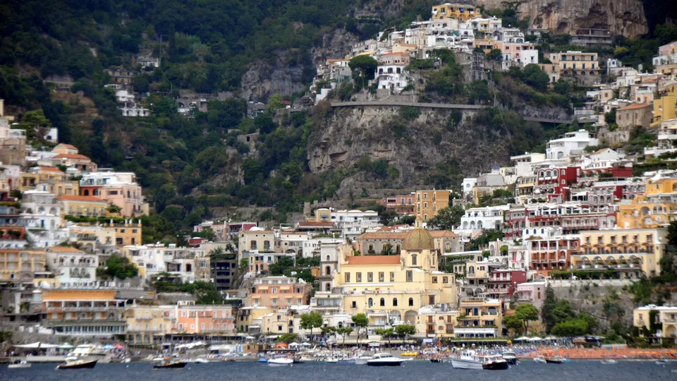 Positano’s colorful buildings rising steeply from the waterfront, seen from the sea