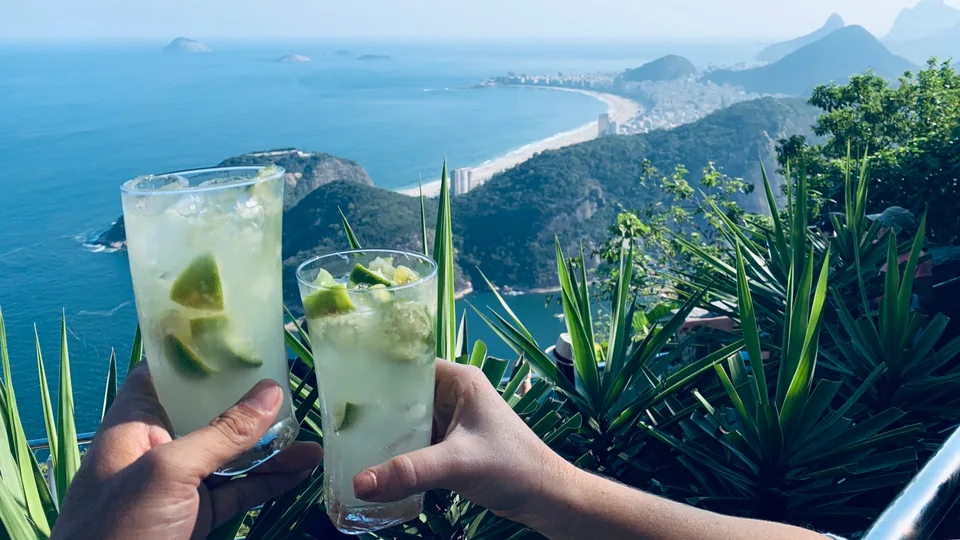 Two lime drinks raised above the coastal view from Sugarloaf