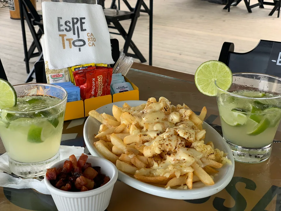 A shared plate with fries, olives and lime drinks on a restaurant table