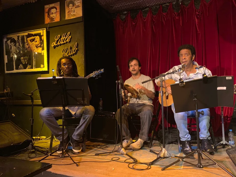 Musicians performing in front of the Little Club’s red curtain