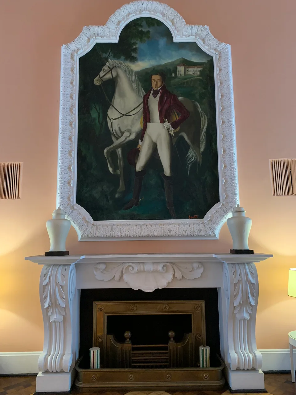 An ornate fireplace and framed artwork inside Quitandinha