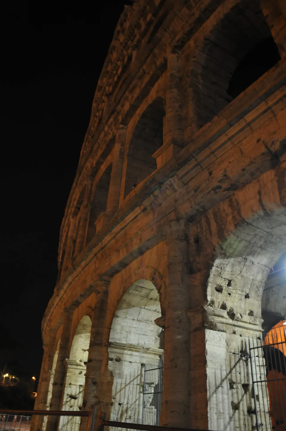 Vista de baixo dos arcos e das pedras desgastadas do Coliseu iluminado à noite