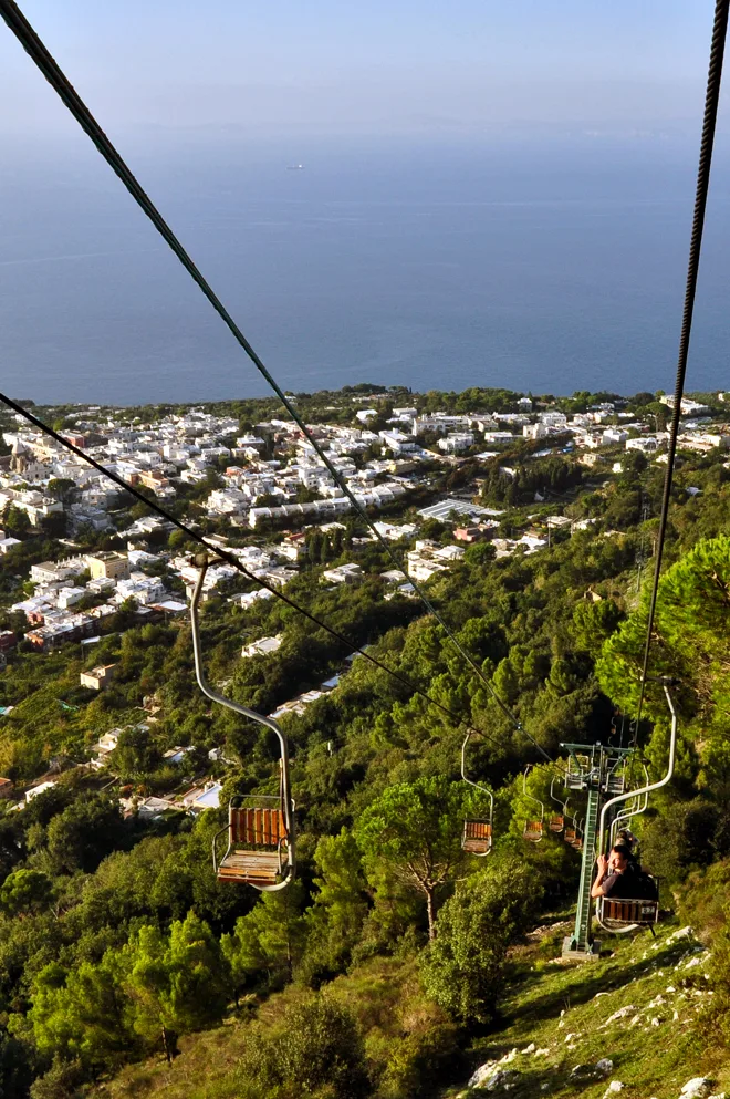 Cadeiras abertas individuais sobre as encostas verdes de Anacapri, com o mar ao fundo