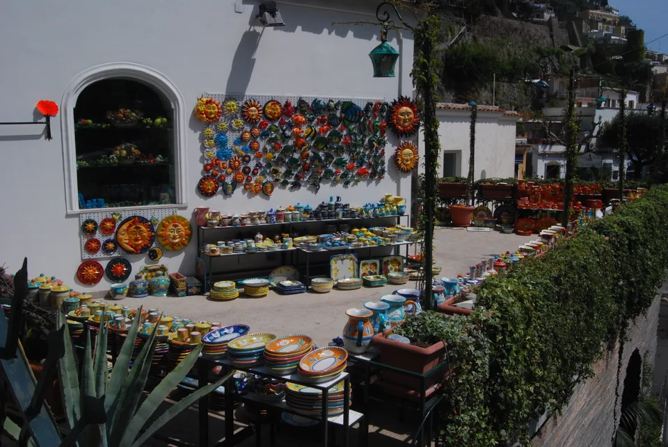 Pratos de cerâmica coloridos expostos num muro branco na entrada de uma loja em Positano