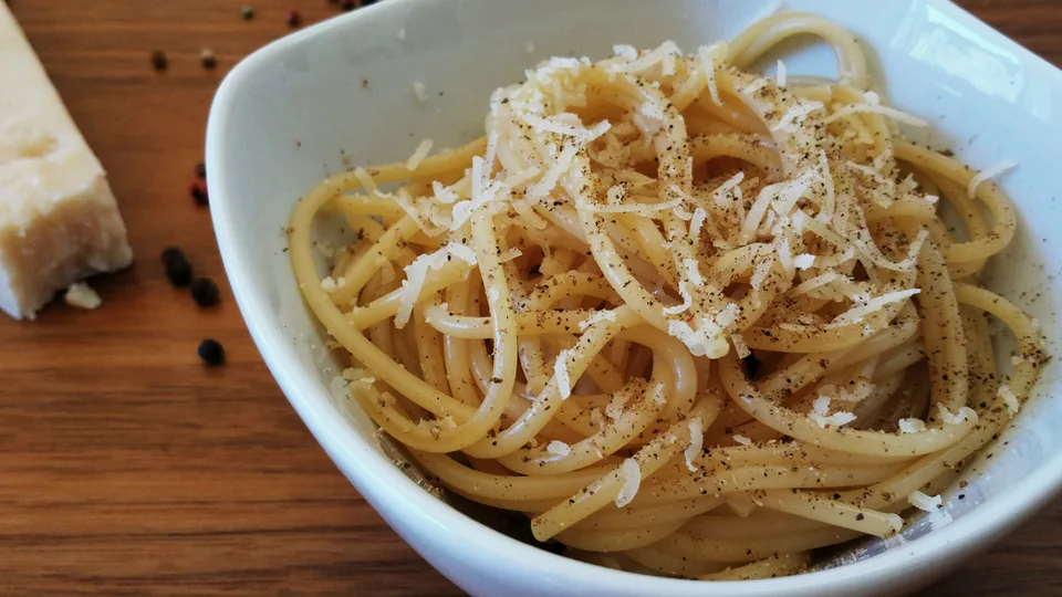 Massa coberta de queijo pecorino e pimenta-do-reino numa tigela branca